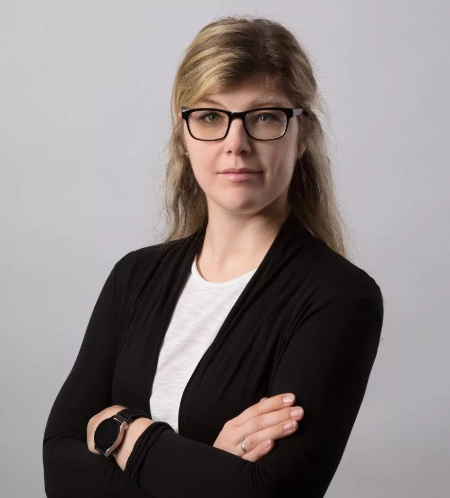 Frau mit verschränkten Armen, neutral.